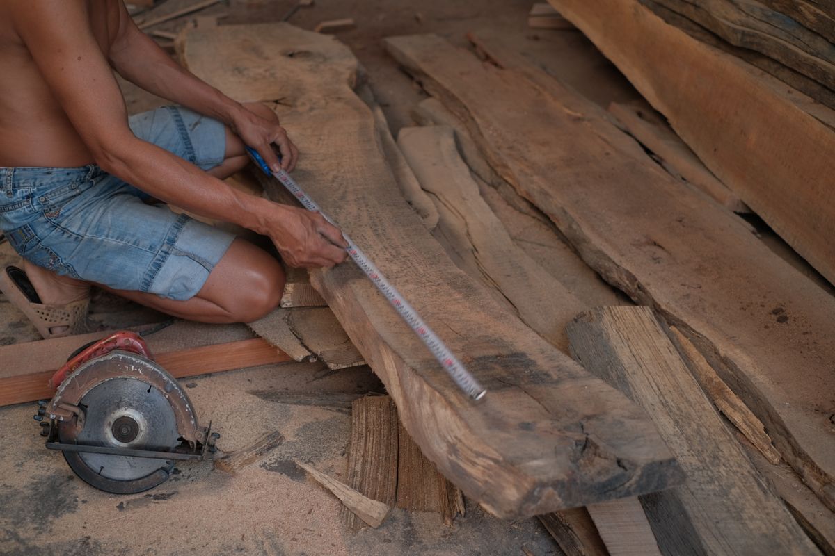 Carpintero midiendo un tablero de madera en el taller